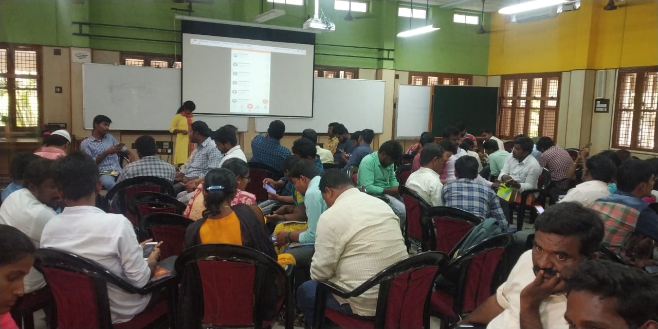 A full hall of extension workers following a projected demonstration and working through the field activity app on their own phones