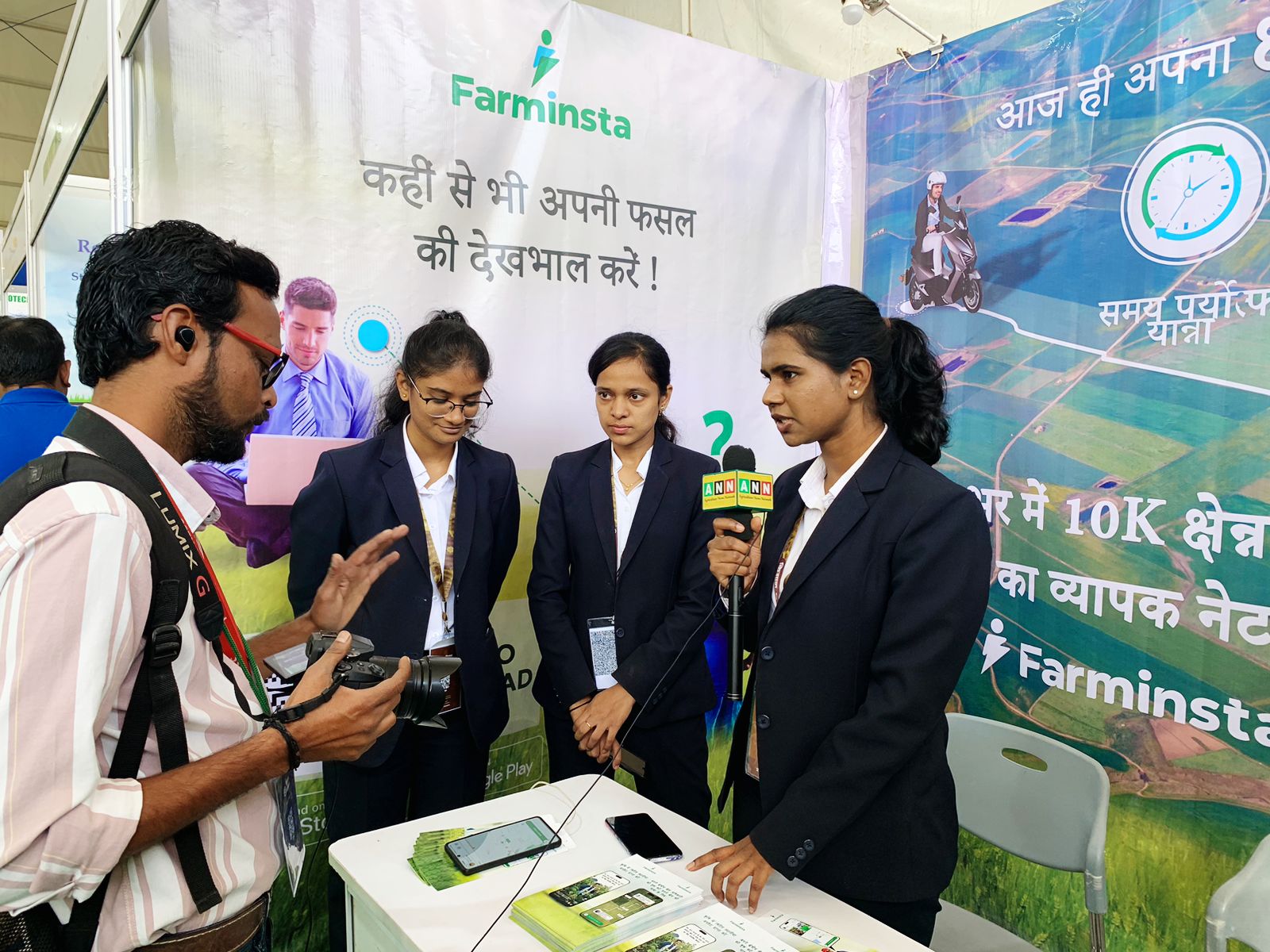 A Farminsta team member being interviewed at the farmer app launch stand, with two colleagues and the Farminsta banner behind